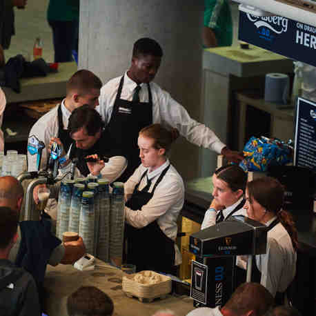 7 young members of the bar staff working the bar at an event.