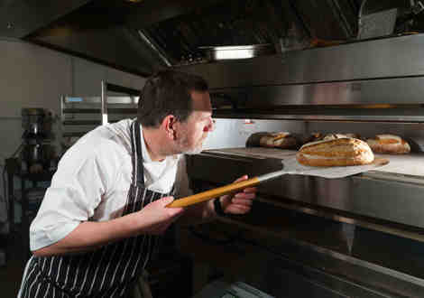 A chef removing a loaf of bread from an oven.
