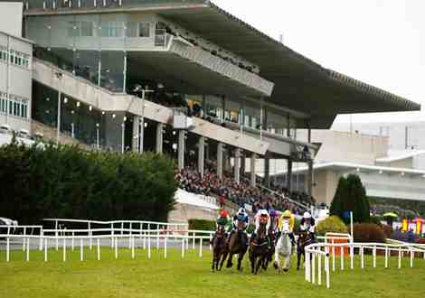 Horses racing past the crowd and stand at Leopardstown racecourse.